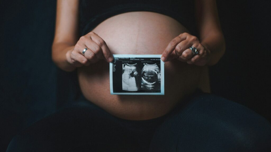 a pregnant woman holding a camera in her hands