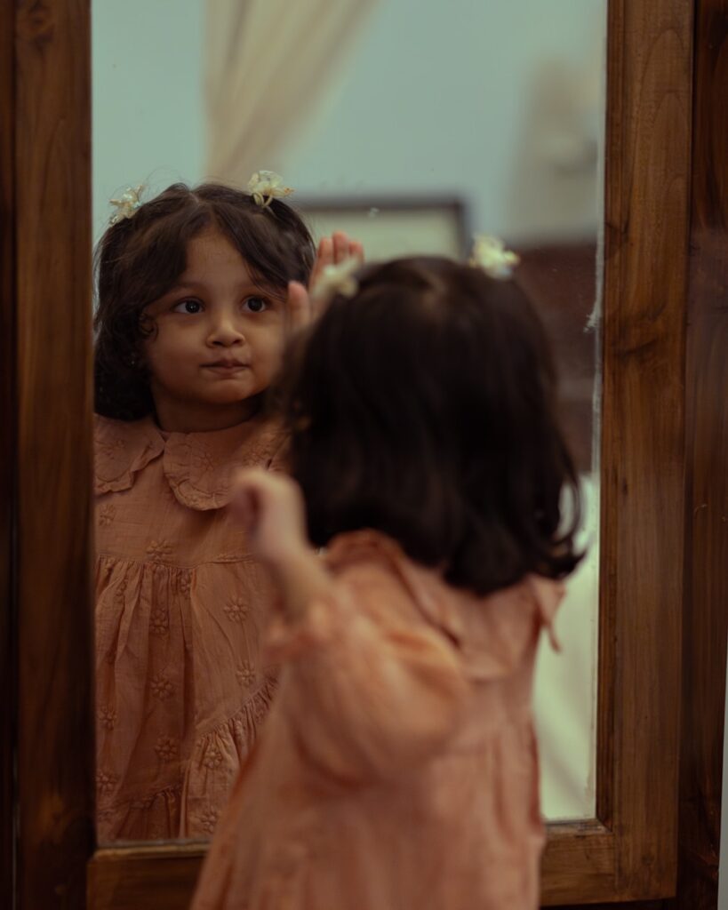 a little girl standing in front of a mirror