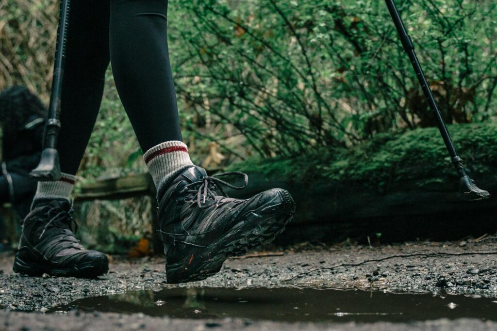 Close-up of hiker's boots splashing through a puddle on a forest trail.