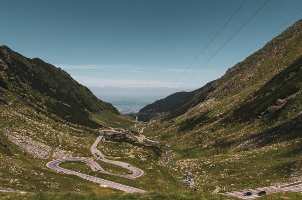 gray asphalt road between green mountains under blue sky during daytime