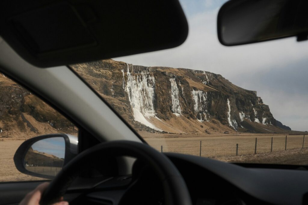 A person driving a car in front of a mountain
