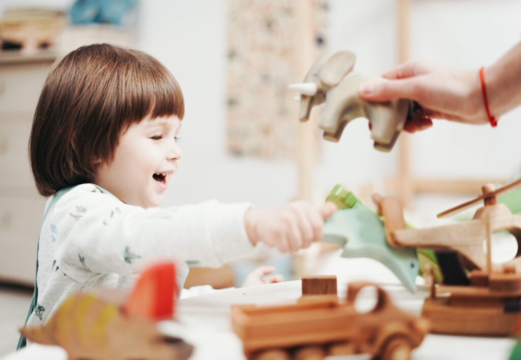 Smiling child playing and exploring with wooden toys in a bright room, fostering creativity.