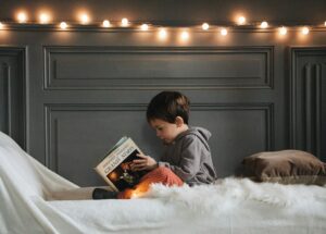 boy reading book on bed